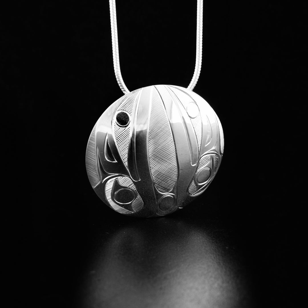 Sterling silver round raven pendant hand-carved by Haisla artist Hollie Bartlett. 1.25" in diameter. Hidden bail on back. Chain not included.