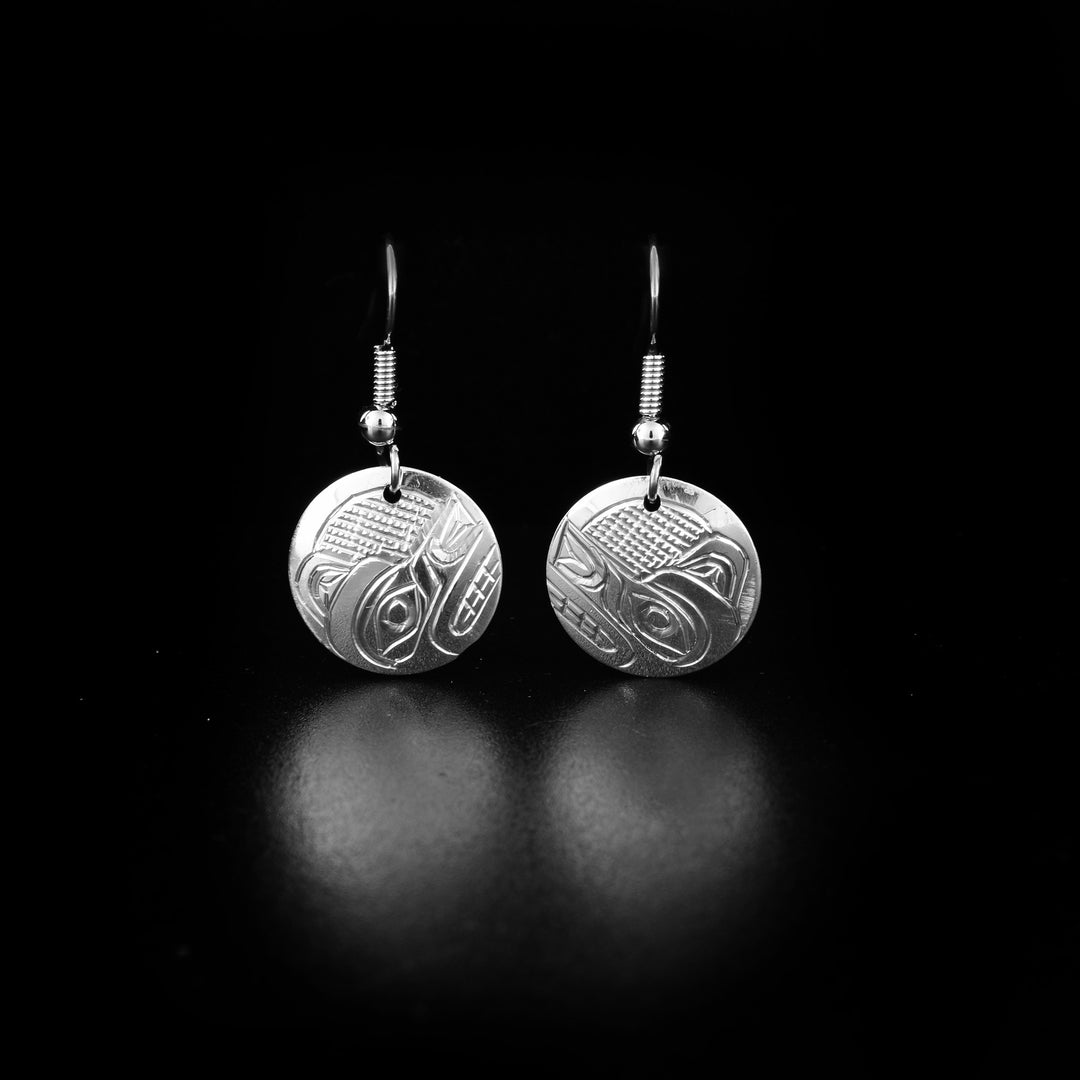 These Wolf earrings are made from sterling silver and have small, circle shaped hangs. There are depictions of the Wolf carved into the surface of the hangs.