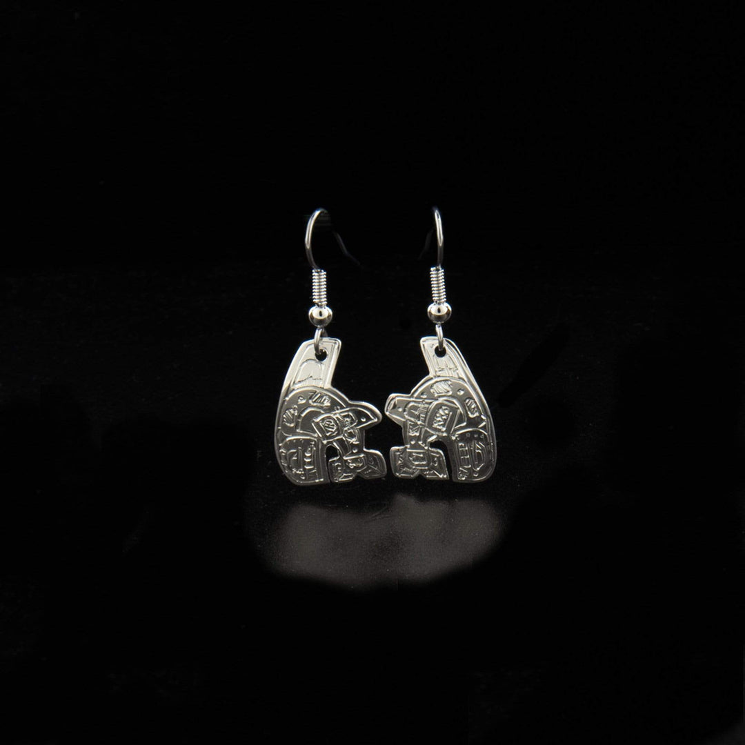 These dangling Orca earrings are made from sterling silver and have hangs shaped like and has carvings on the surface of it depicting the Orca.