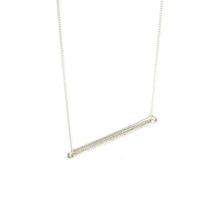 This elegant bar necklace is made from sterling silver and has a thin, horizontal bar pendant. There are patterns carved into the surface of the pendant giving the piece a striking look.