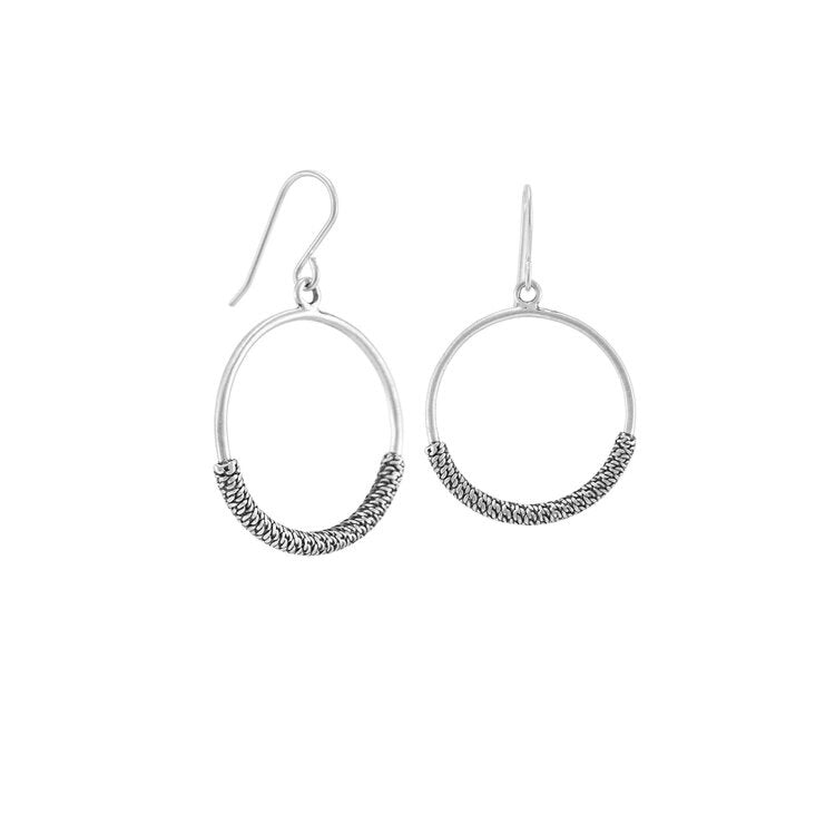These sterling silver dangle hoop earrings have thin hoops that dangle from the hooks. There is a textured cylinder resembling chain mail wrapped around the bottom portion of the hoops.