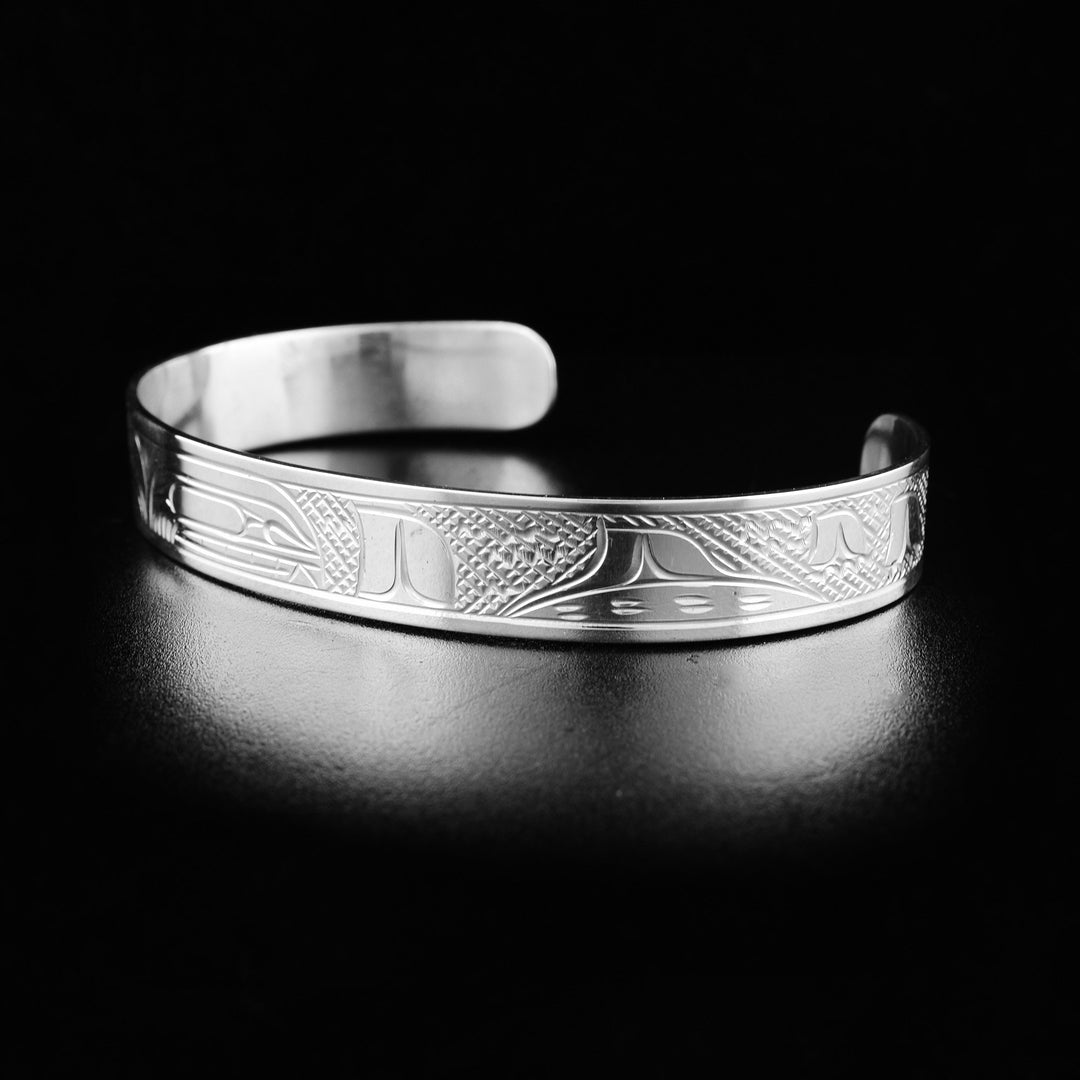Sterling silver orca pod bracelet hand-carved by Kwakwaka'wakw artist Victoria Harper. 6.13" long with 1.38" gap. 0.38" wide.