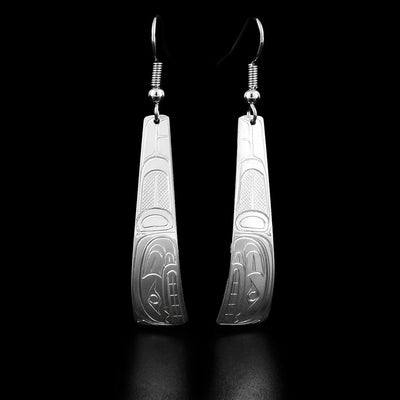These orca earrings are triangle shaped and have the profile of an orca's head with a sneer facing downwards. Behind the head are carved designs representing the orca's fin.