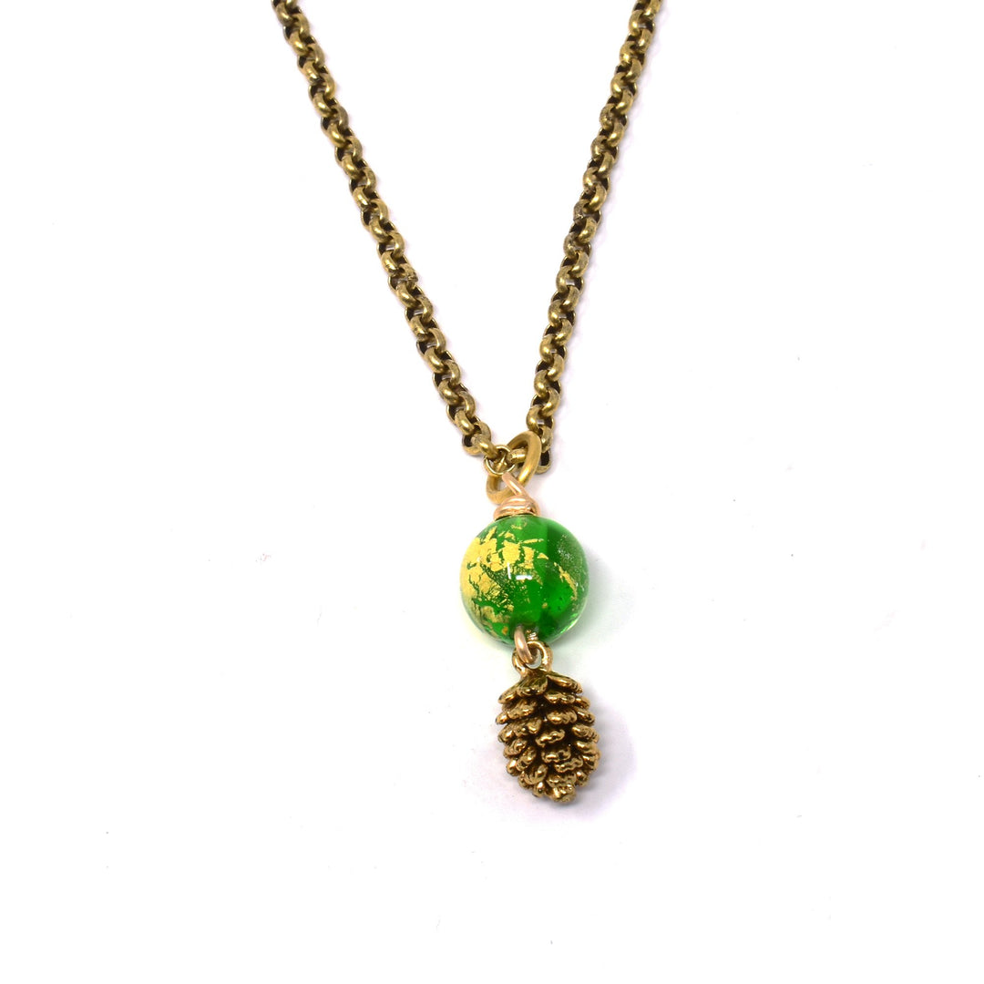 This pinecone necklace is made from  a green lampworked bead with gold leaf, a brass chain and a detailed, gold plated pinecone charm. The brass chain has a green, glass bead with gold leaf in it and a gold filled pinecone charm below the bead.
