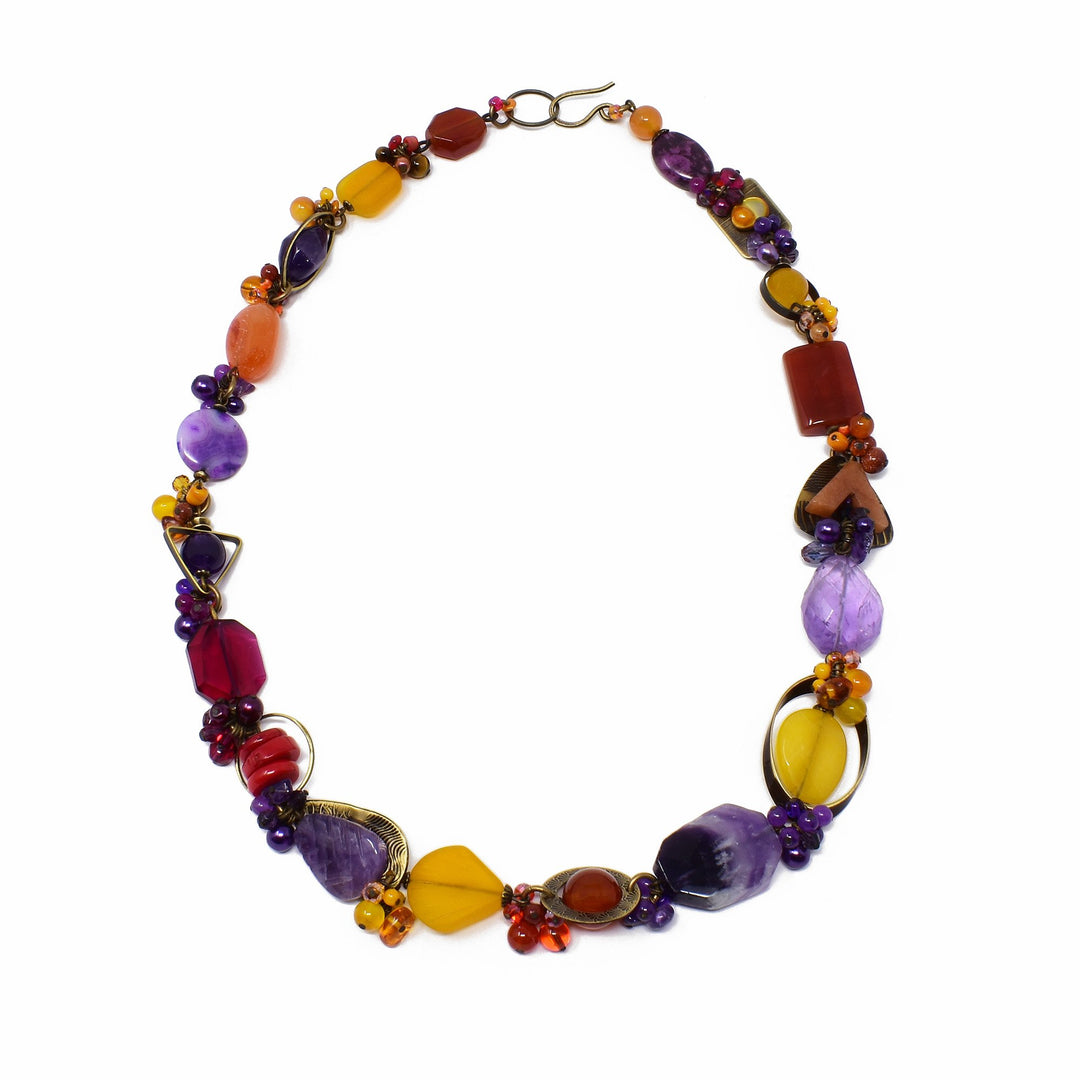 This crystal bead necklace is made from carnelian agate, Swarovski Crystal, lampworked glass, mother of pearl, hand-worked brass, agate, glass, amber, goldstone and tiger's eye. The breads run across the entire piece and are slightly larger at the bottom of the necklace. Each of the beads has a unique shaped, design and material.