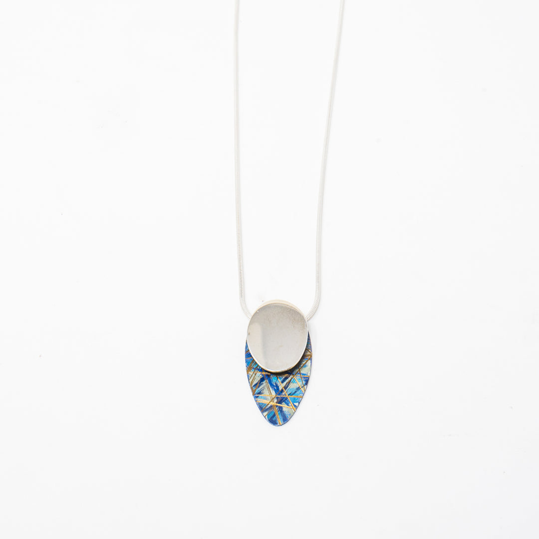 This dainty titanium necklace pendant is made from sterling silver and anodized titanium. The piece have a silver circle with a teardrop shape titanium piece at the bottom depicting a shadow. There are brilliants colors and designs on the titanium which are achieved by anodizing the metal.