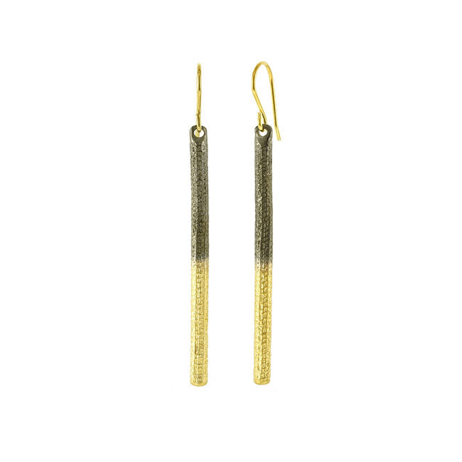 These silver and gold drop earrings are made from oxidized sterling silver and 18K gold plated material. The hangs are vertical rods and have marking carved into them giving them a textured look. There top half of the hangs are made from oxidized silver and the bottom half is gold plating.