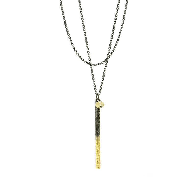 Two-Tone Textured Bar Pendant Necklace handcrafted by artist Dushka Vujovic. Pendant made of oxidized sterling silver, 18K gold plating and a rutilated quartz roundel bead. Oxidized sterling silver chain included. Pendant measures 2.13" x 0.13" including bail. Chain is 32.25" long with 2" extender.