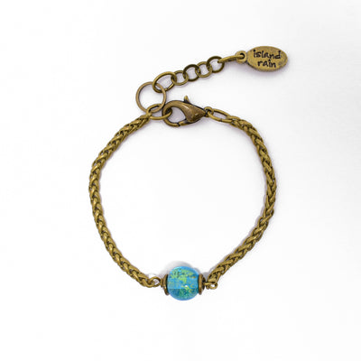 Urban Tribe Brass Bracelet by Wendy Pierson. Made of brass and a handmade lampworked glass bead. Bracelet is 6.38" long with 1.25" extender. Central bead is 0.38" in diameter.