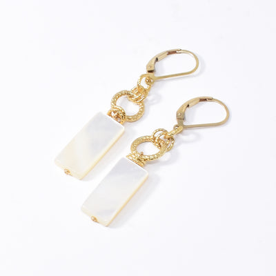 White Mother of Pearl Rectangle Earrings handcrafted by artist Karley Smith. She has used mother of pearl and gold-plated wire and adornments to create them. Ear hooks are gold-filled. Each earring measures 1.80" x 0.30" including hook.