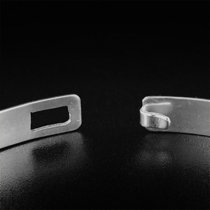 This sterling silver bangle bracelet has a thin band and a clasp in the back. There are depictions of the Eagle and the Hummingbird carved into the surface of the band.