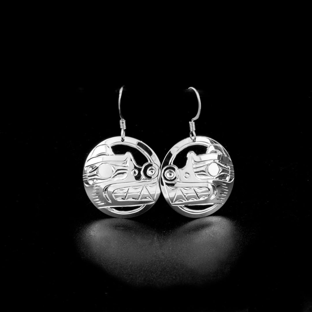These dangling Bear earrings are made from sterling silver and have circle shaped hangs. There are cutouts and carvings on the surface of the hangs depicting the Bear.