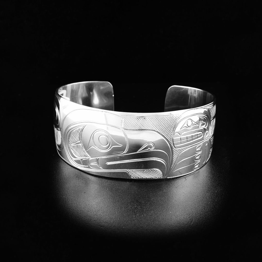 An Orca and Eagle sterling silver cuff bracelet. It is handcarved, and depicts the face and wing of the Eagle, and the face and body of the Orca in the center of the bracelet.