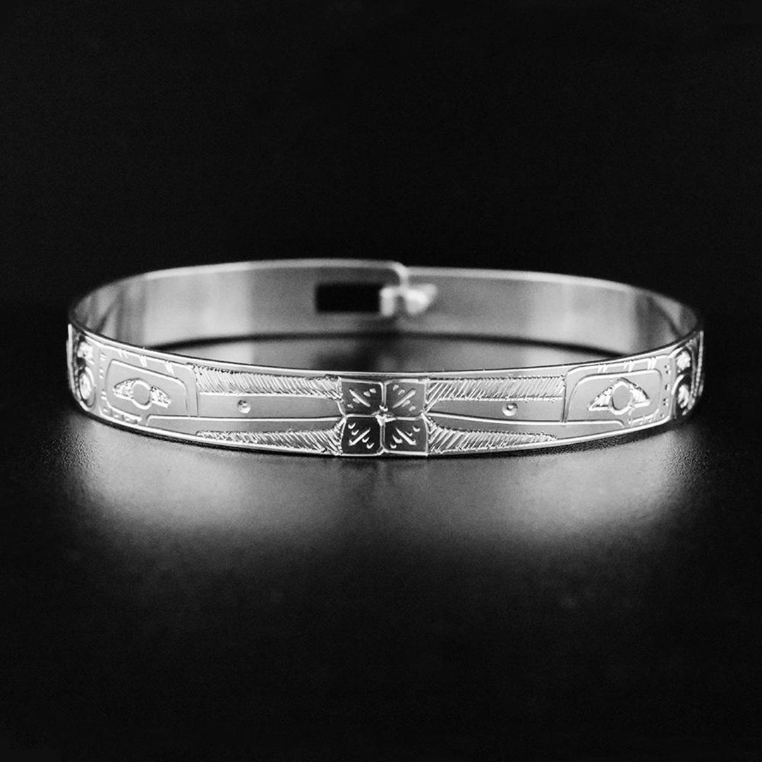 Sterling silver Hummingbirds and flower clasp bracelet. In the center of the bracelet the artist has hand-carved a dainty, four-leaf flower. On both sides of the flower there are the profile of the heads of two hummingbirds both drinking from the flower. Both hummingbirds have a feather on their head and long, narrow beaks.