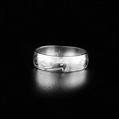 This silver ring has the profile of an eagle's head facing the right and the profile of an orca's head facing the left, looking at one another.
