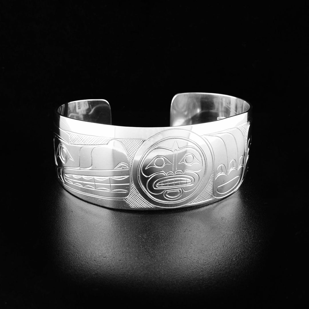 A sterling silver cuff Wolf and Moon bracelet. The handcarved design depicts the face of the Wolf holding the Moon in its paw.
