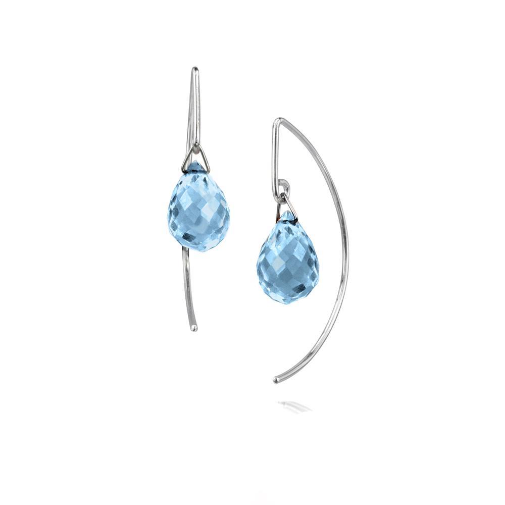 These dangling blue topaz earrings are made form sterling silver and blue topaz gems. There are large, oval topaz gems dangling under the hooks and the silver hooks curve around the back of the ear and drops below the gems.