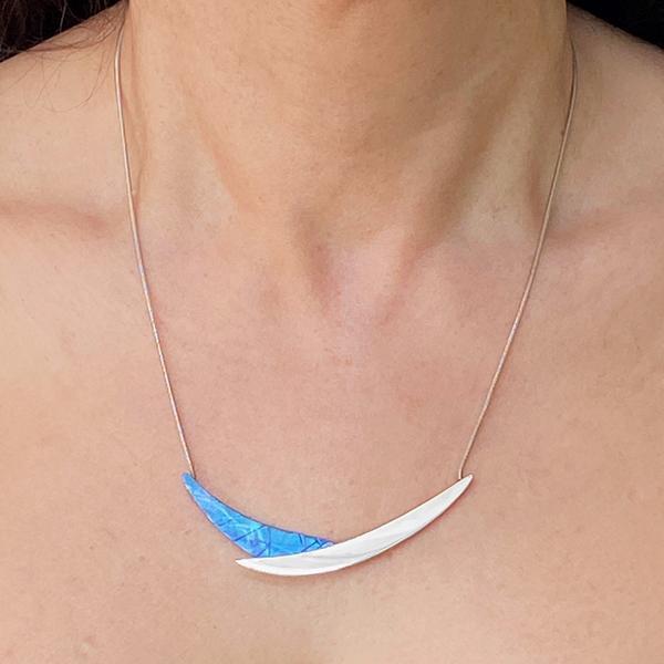 This silver and titanium necklace is made from sterling silver and anodized titaniumthe pendant is made of an anodized titanium piece and a silver piece that are connected to form a cradle shape.
